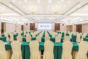 A conference room with rows of tables and chairs, a projection screen, and chandeliers. - The Center Hotel (Yantai)