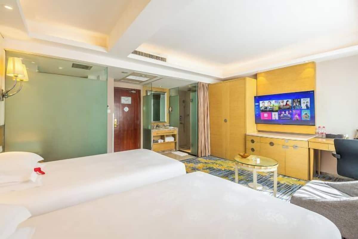 A hotel room with a bed, a desk, a television, and a mirror.