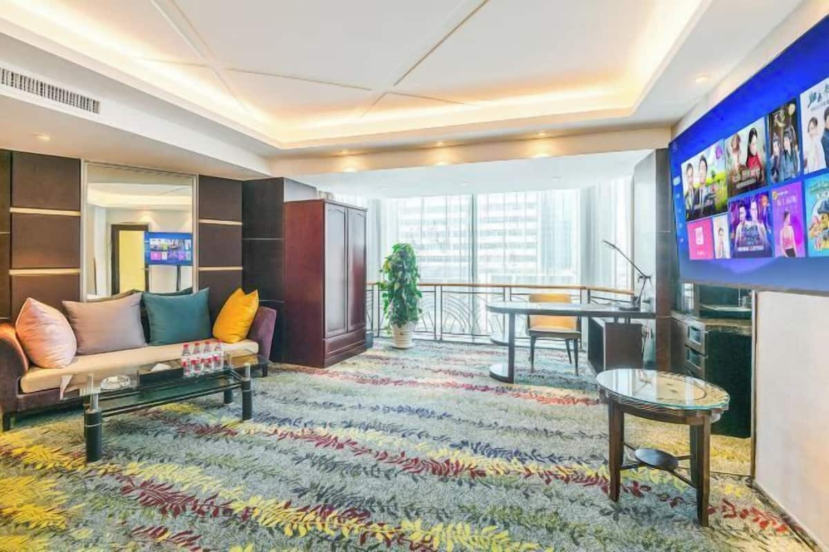 A hotel lobby with a sofa, a coffee table, a TV wall, and a large window.