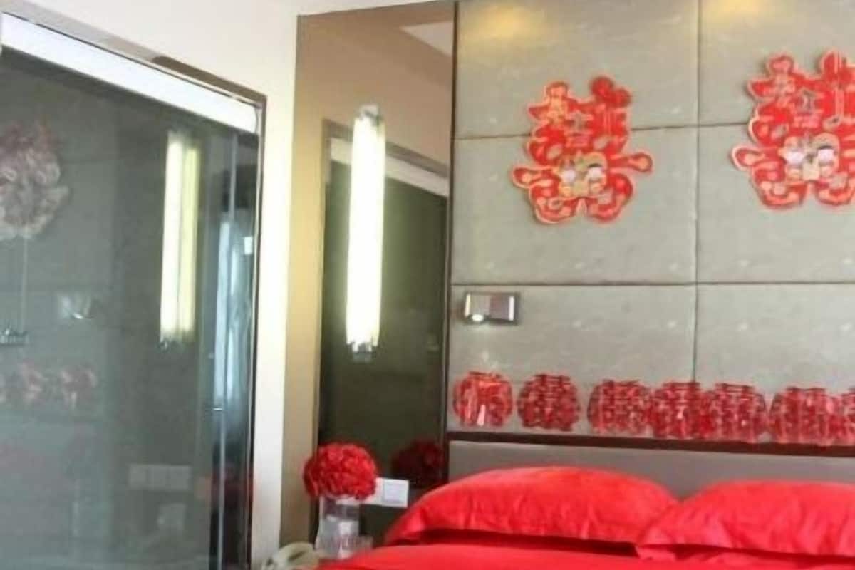 A modern hotel room with a large bed, a glass door, and decorative wall art.