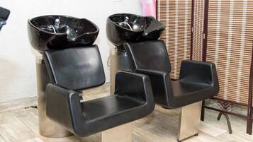 Experience a professional and uncluttered space with two salon chairs, a wooden chair, and a metal table.
