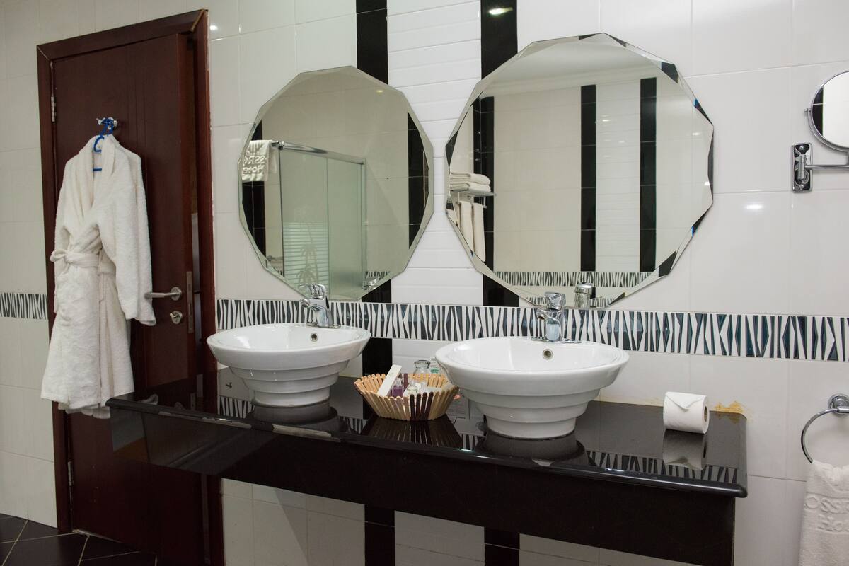A bathroom with two sinks, a large mirror, and a towel rack.