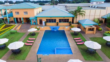 Una piscina al aire libre, sombrillas, sillones reclinables de piscina