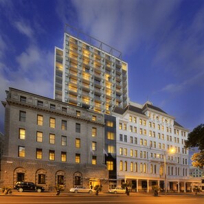 A multi-story hotel with a mix of modern and classical architecture, featuring a prominent glass facade and a traditional building with arched windows.