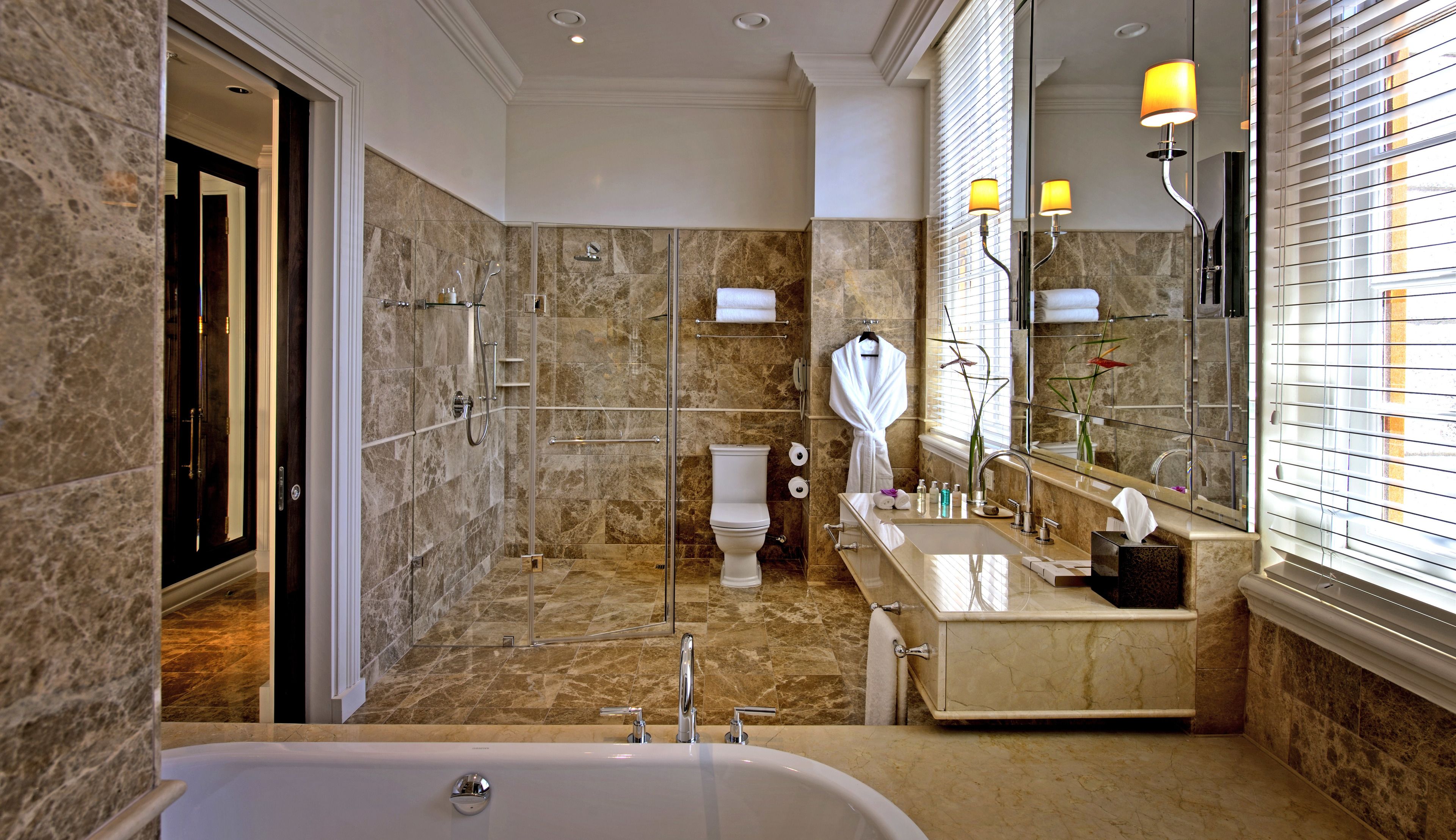 A modern bathroom with a bathtub, a glass-enclosed shower, a toilet, and a vanity with a mirror.
