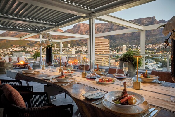 An outdoor dining area with a view of a city and mountains. - Taj Cape Town (Cape Town)