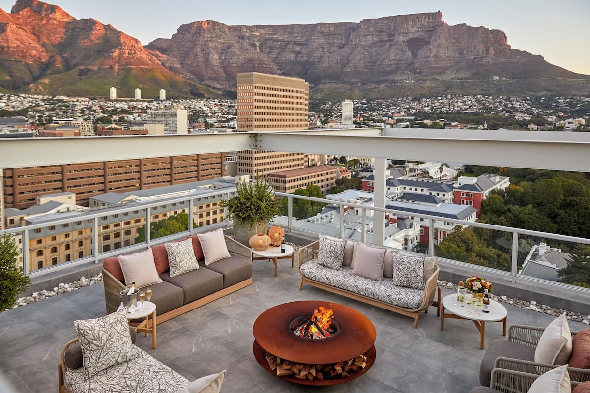 Une terrasse sur le toit, dotée d’un foyer, de canapés et offrant une vue sur le paysage urbain et les montagnes.