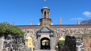 Un edificio histórico con una torre central, paredes de piedra y una entrada arqueada.