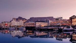 A waterfront cityscape with a prominent Ferris wheel, historic buildings, and a marina with boats. - Taj Cape Town (Cape Town)