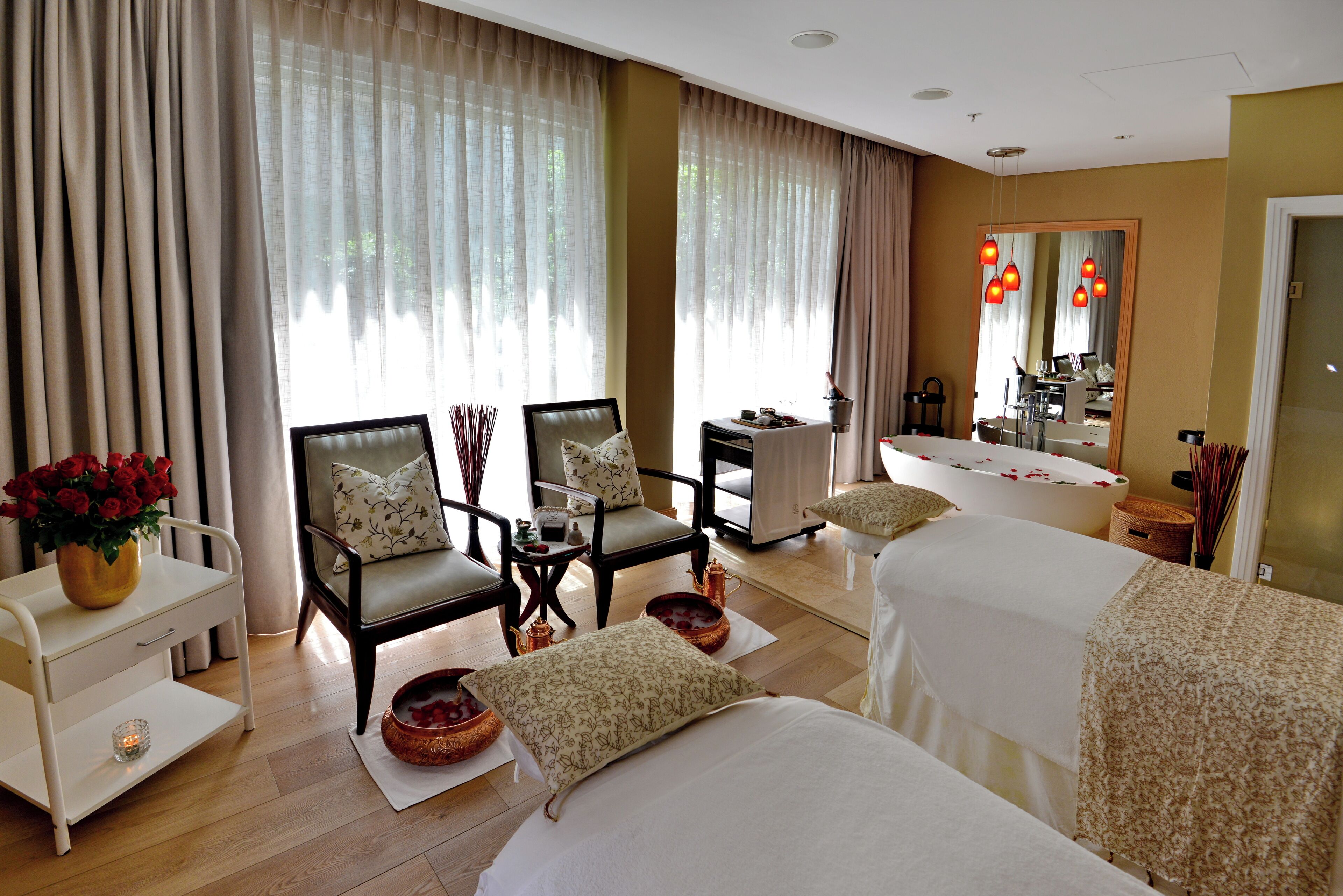 A hotel room with two beds, a sitting area with chairs, a small table, and a large mirror.