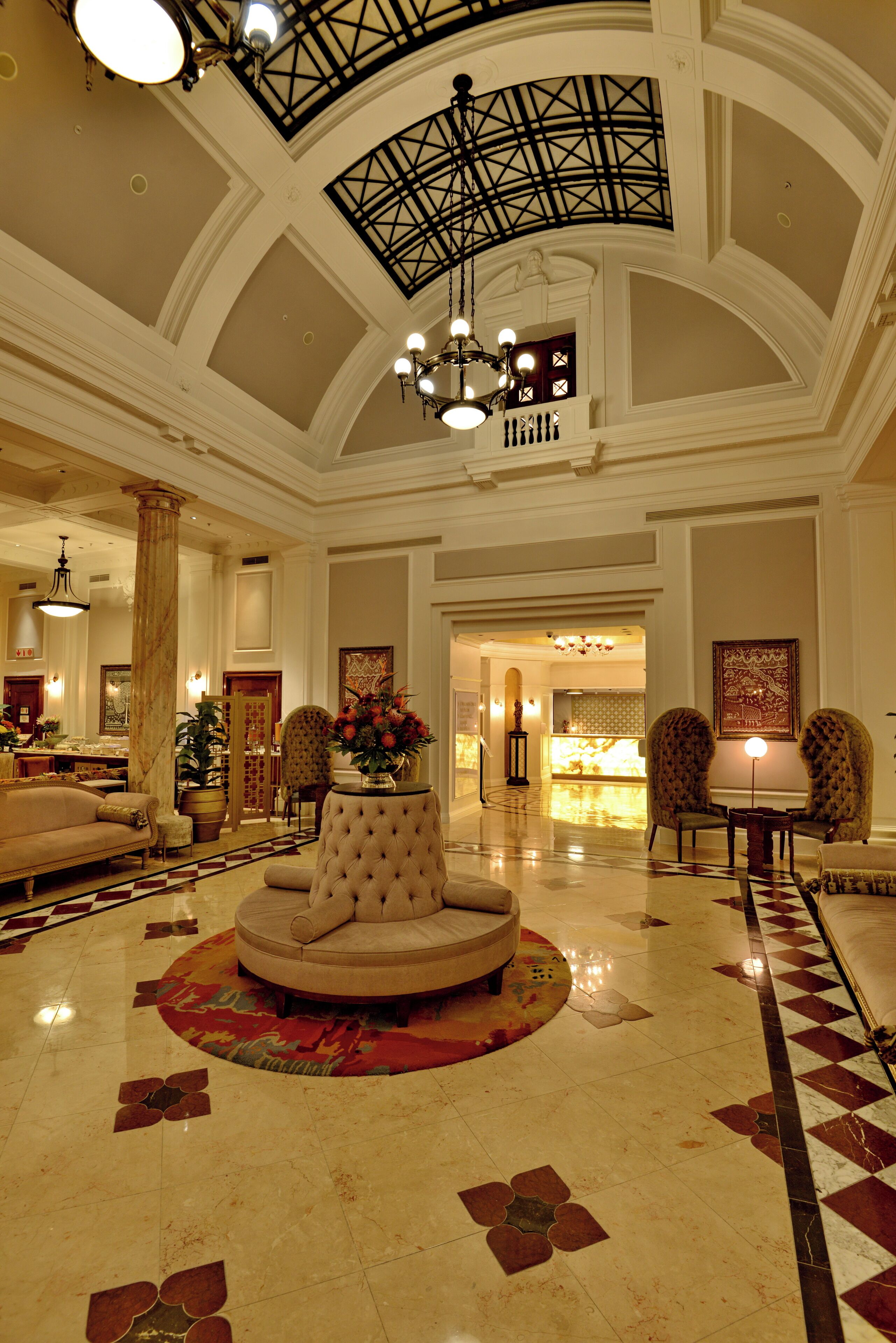 A spacious lobby with a high ceiling, a central round seating area, and a checkered floor pattern.