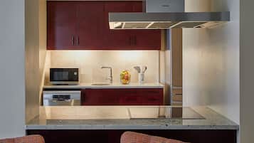 Una cocina moderna con armarios rojo oscuro, un microondas de acero inoxidable y un horno empotrado.