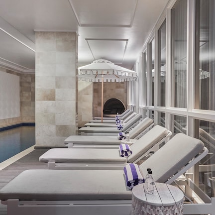 A row of sun loungers by a pool with a view of a building in the background.
