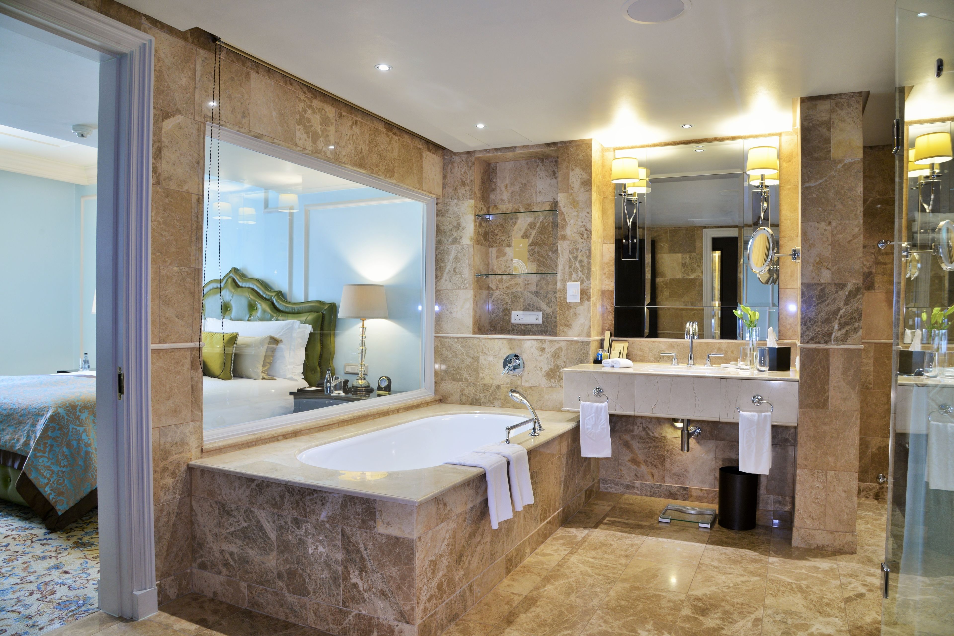 A modern bathroom with a large mirror, a bathtub, a double sink, and a shower area.