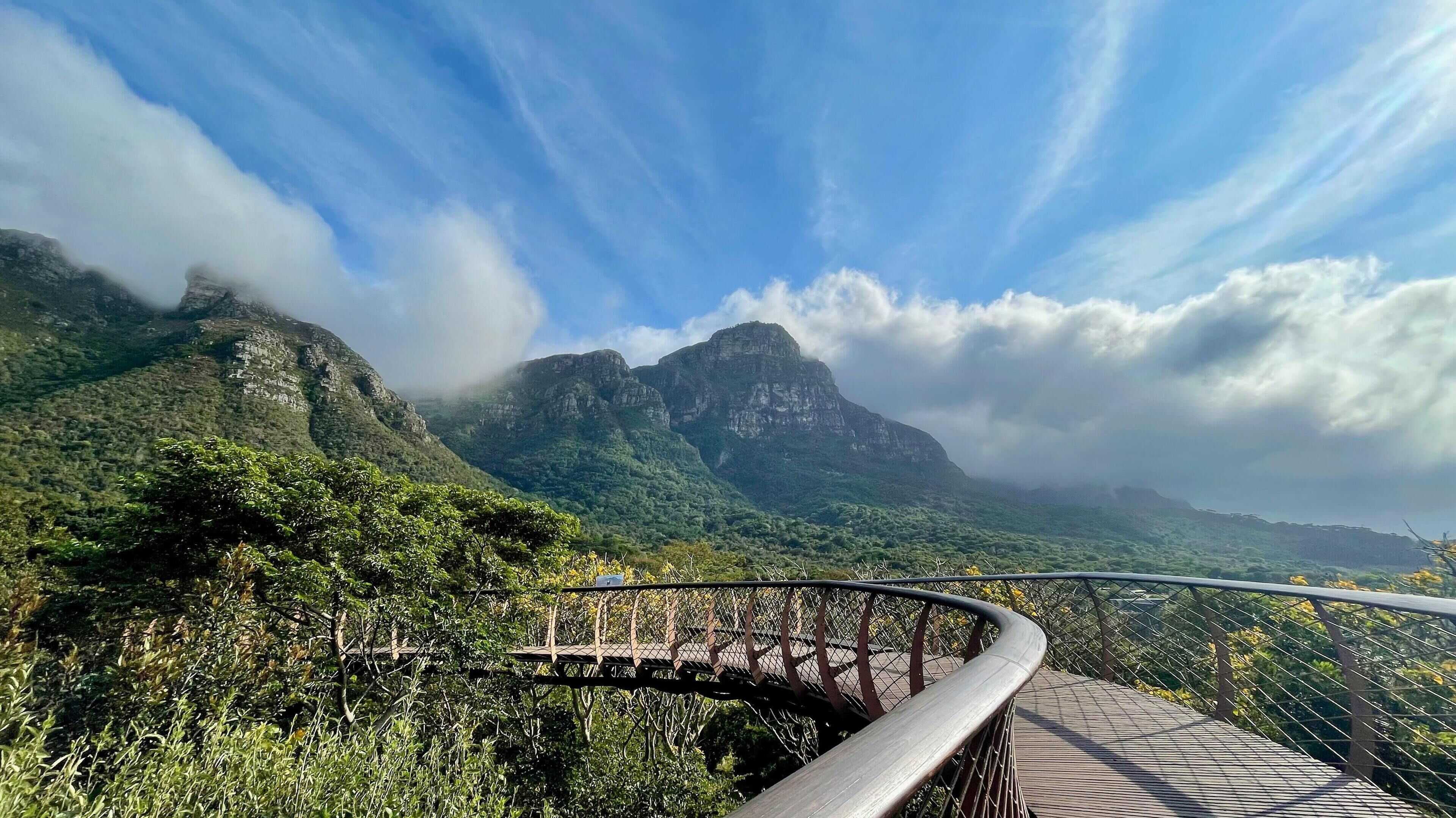 A scenic mountain view with a wooden bridge and a metal railing.