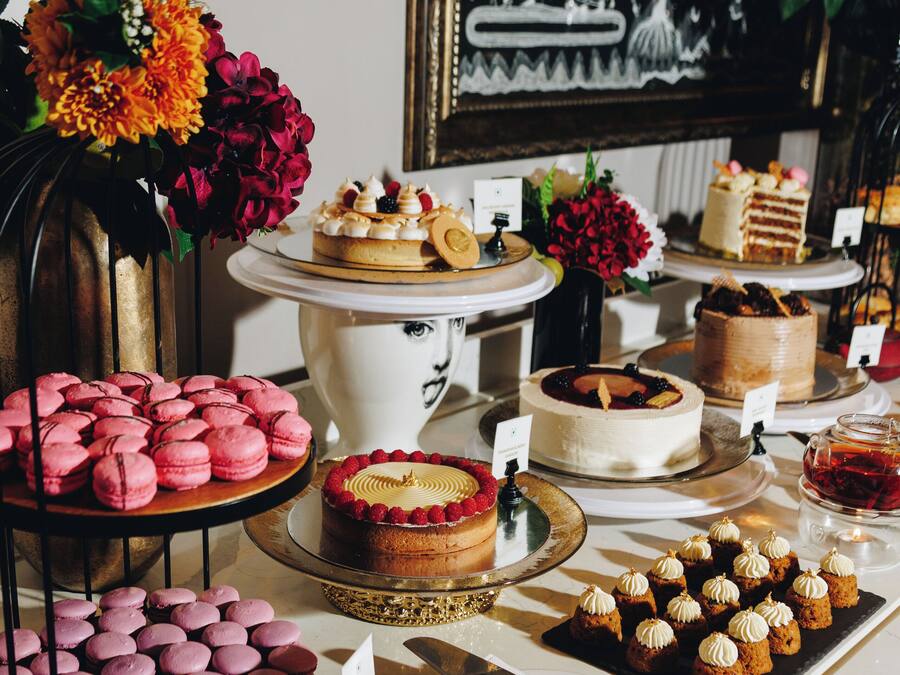Una mesa de postres con varios pasteles, macarons y repostería.