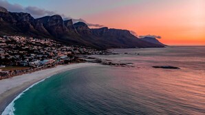 A coastal town with a beach, houses, and mountains in the background. - Taj Cape Town (Cape Town)