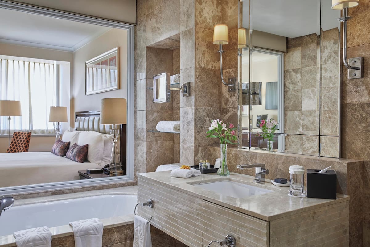 Une salle de bain d’hôtel moderne, dotée d’un grand miroir, d’une baignoire et d’un meuble-lavabo.