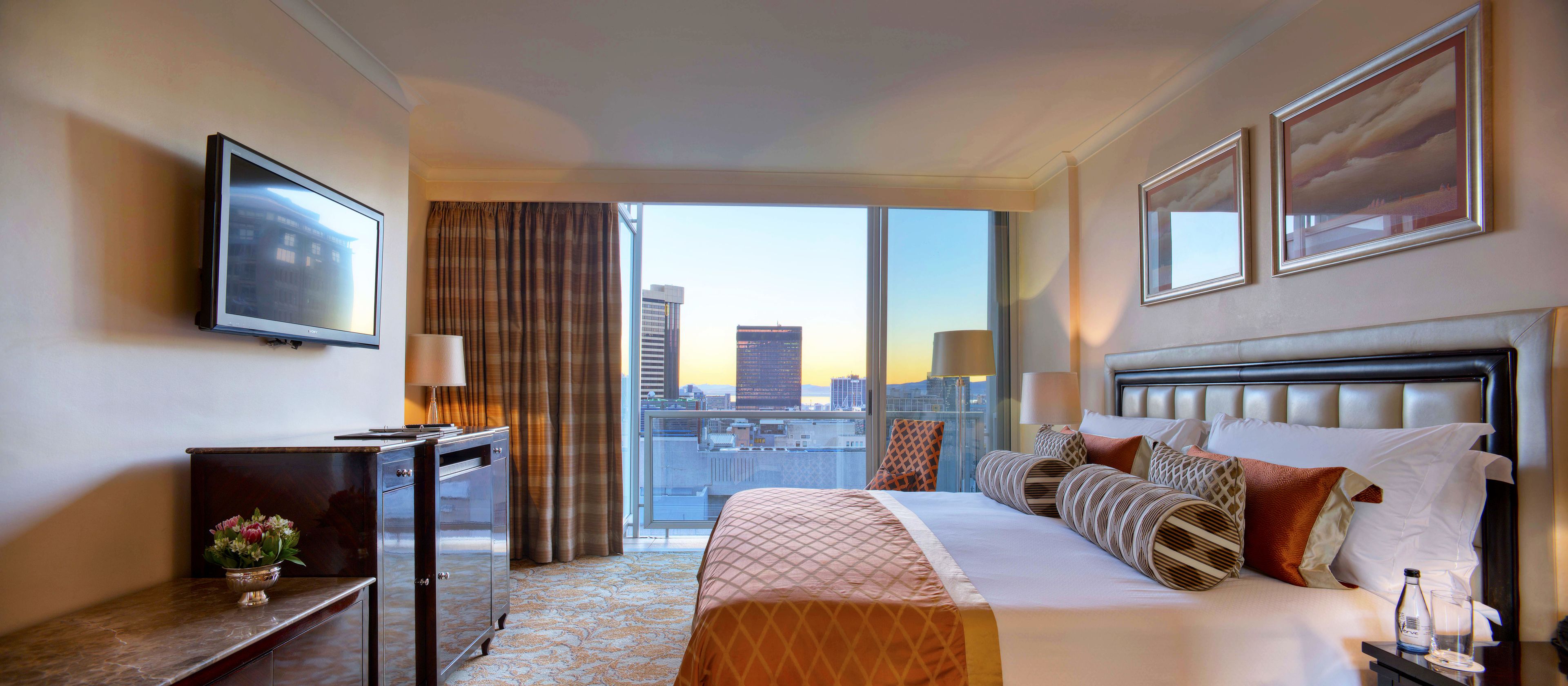 Une chambre d’hôtel avec un grand lit, une télévision, un bureau et une vue sur le paysage urbain par la fenêtre.
