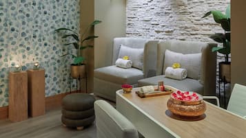 Una sala de estar moderna con un sofá, un reposapiés y una mesa de centro de madera con adornos.