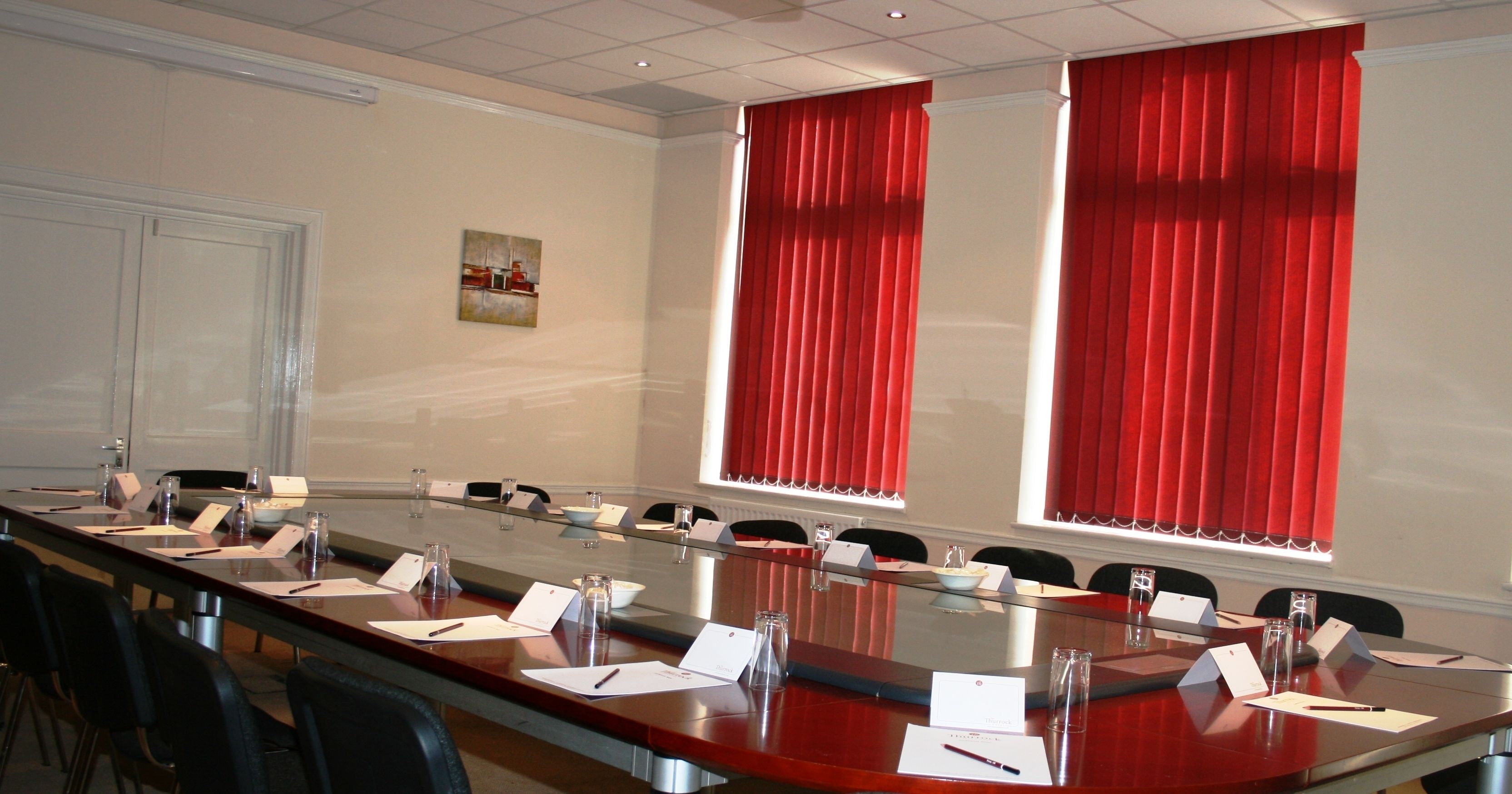 A conference room with a long table, chairs, name cards, and a whiteboard.