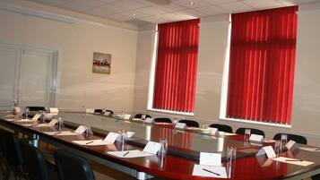 A conference room with a long table, chairs, name cards, and a whiteboard.