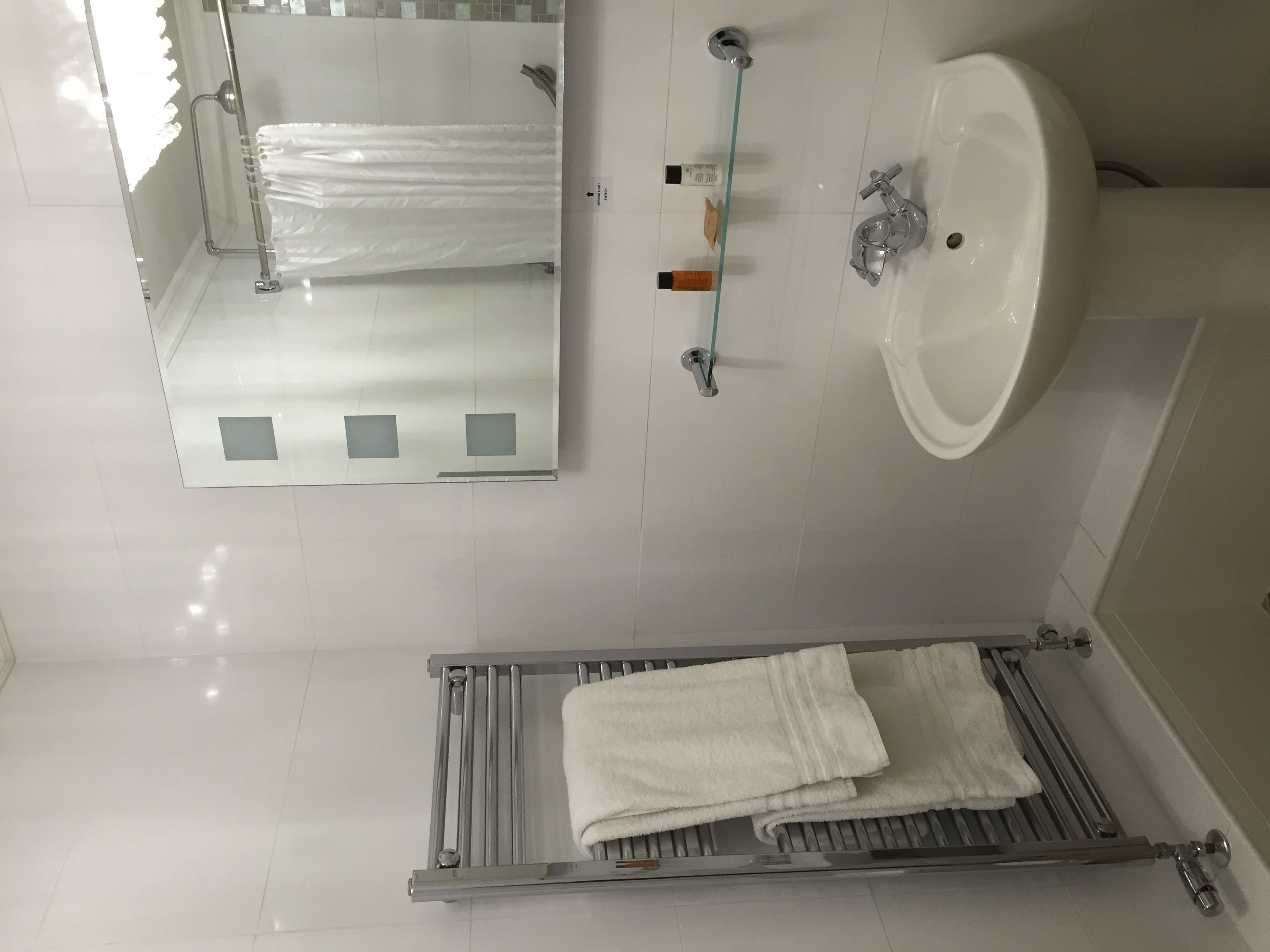 A bathroom with a white sink, mirror, and towel rack.