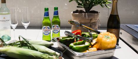 Ein Tisch mit Peroni-Flaschen, einer Weinflasche und einer Pflanze in einem Jutbeutel.
