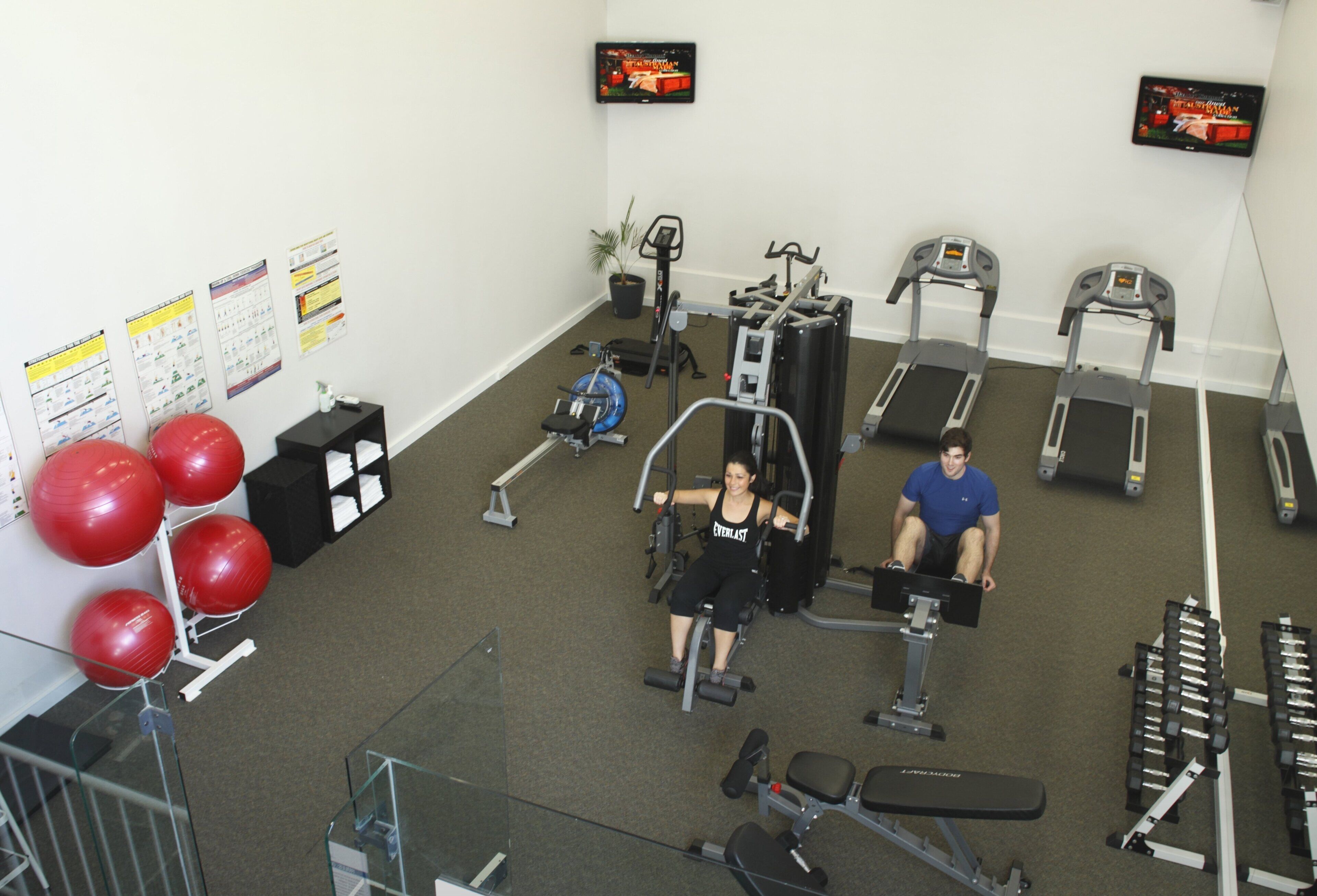 A gym with exercise equipment, a TV, and a staircase.