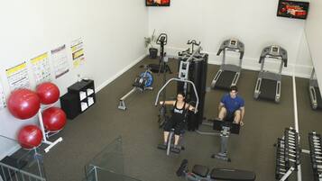 A gym with exercise equipment, a TV, and a staircase.