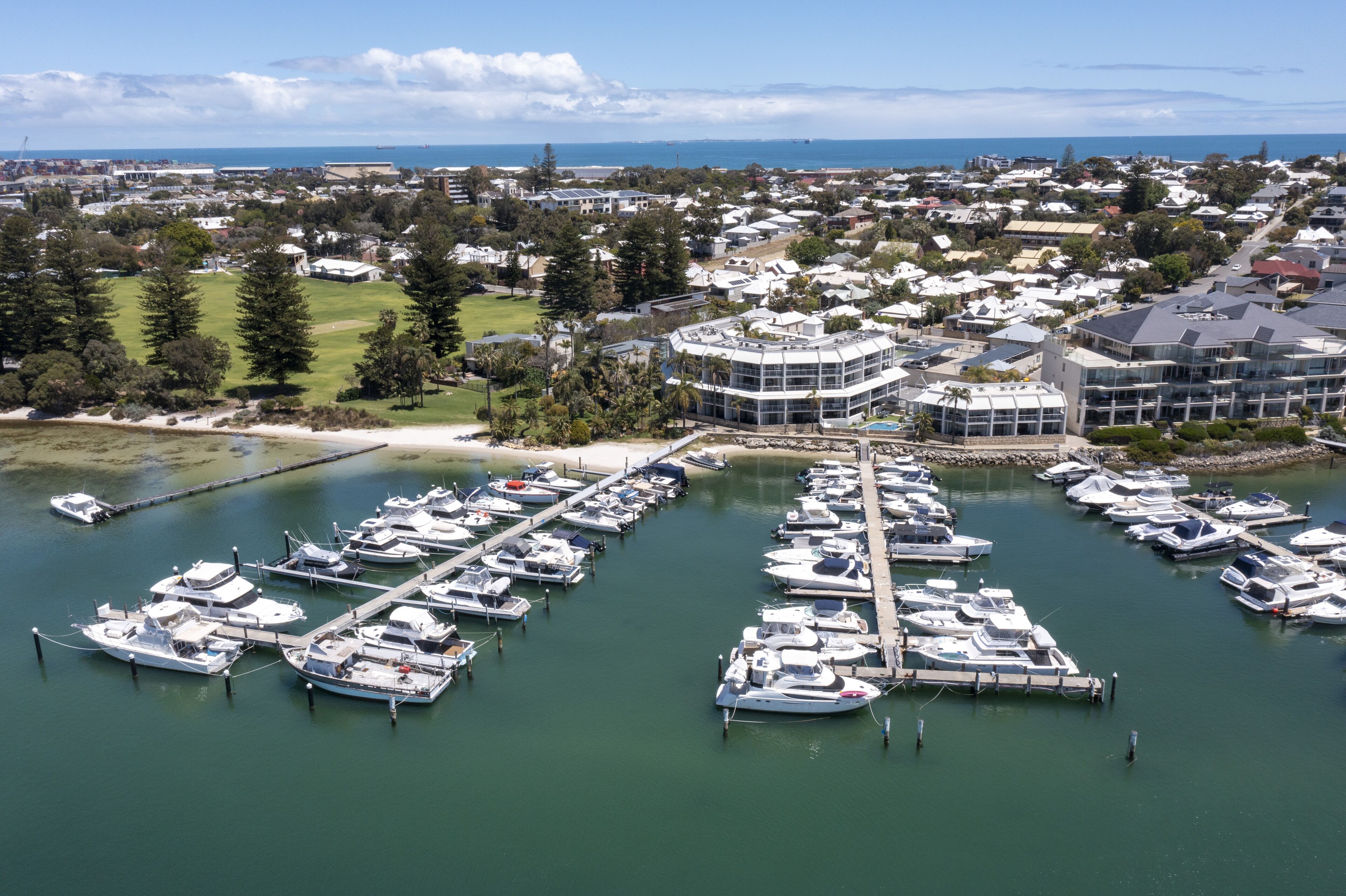 A marina with numerous boats docked, surrounded by residential buildings and greenery.