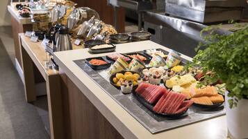 Un buffet proposant une variété de plats, notamment des fruits, des fromages et des viandes.