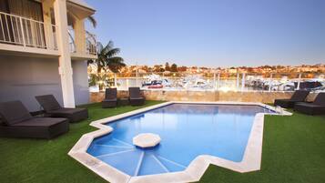 A swimming pool with a view of boats and a building with a balcony.