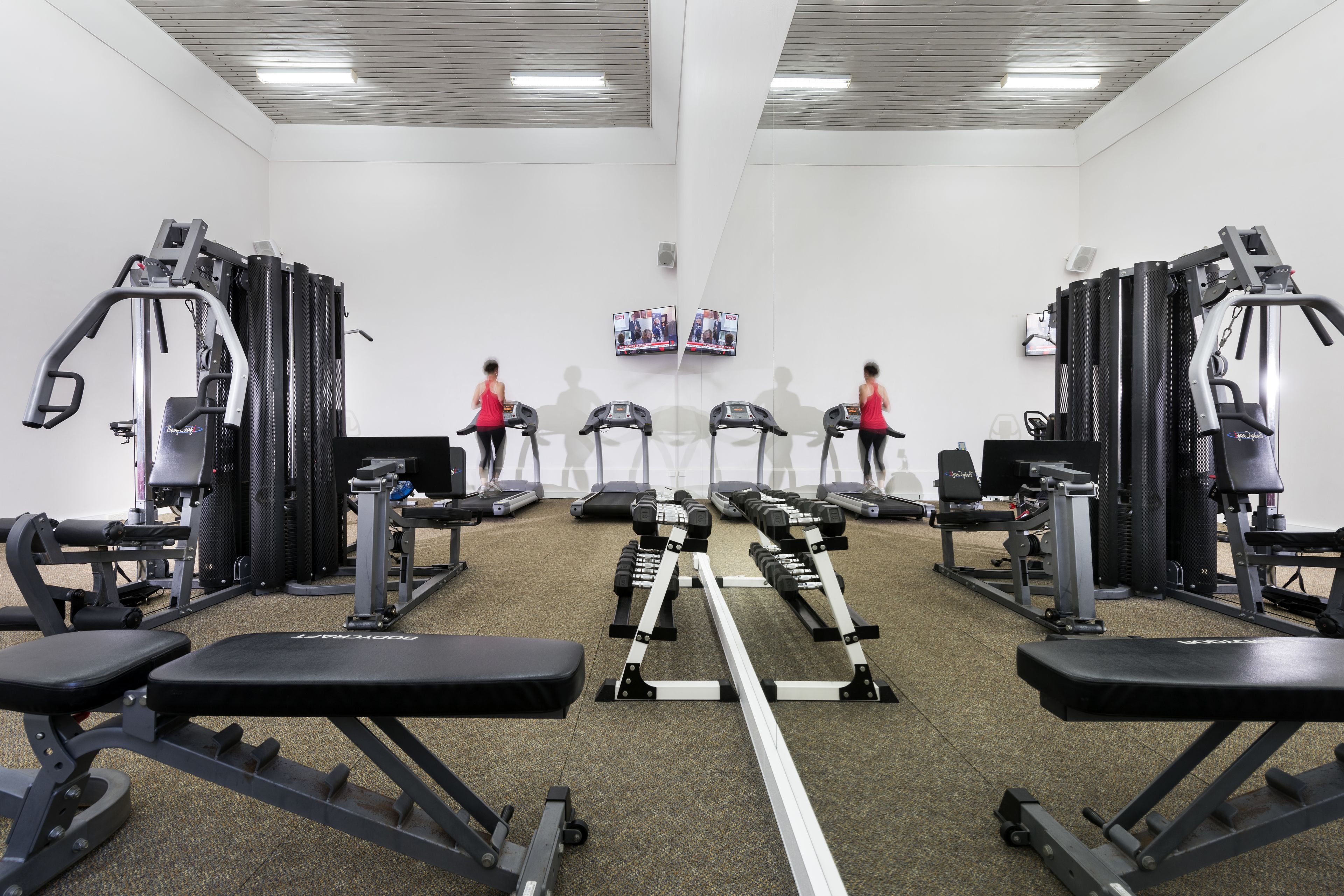 Un gimnasio con cintas de correr, máquinas de pesas y bancos.