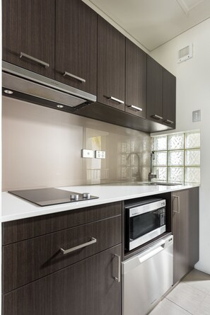 A modern kitchen with dark wood cabinets, stainless steel appliances, and a white countertop.