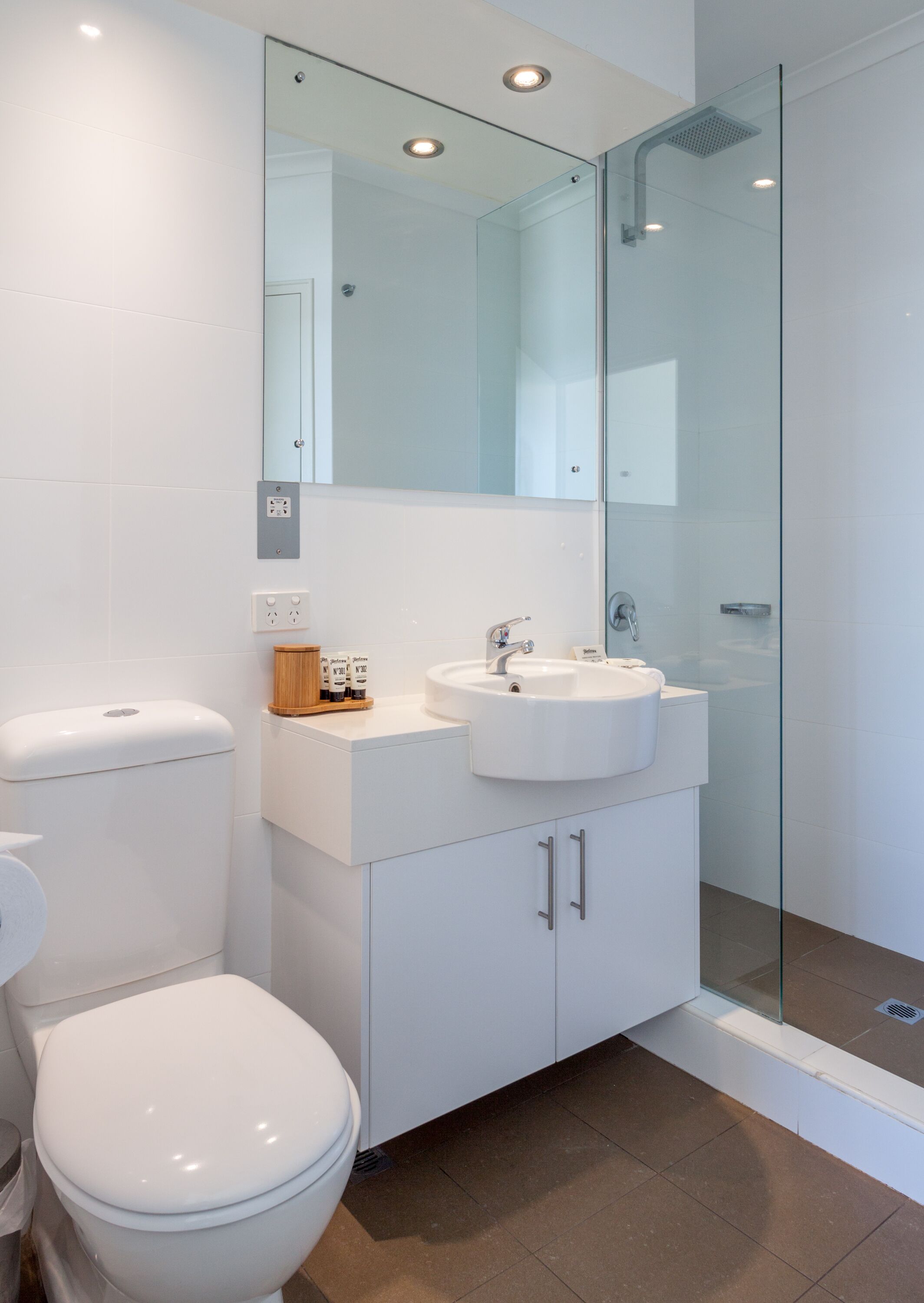 Ein modernes Badezimmer mit Toilette, Waschbecken und einer Duschkabine aus Glas.