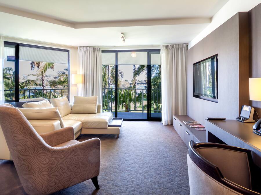 Una habitación de hotel con sofá, una silla, escritorio con teléfono y televisor.