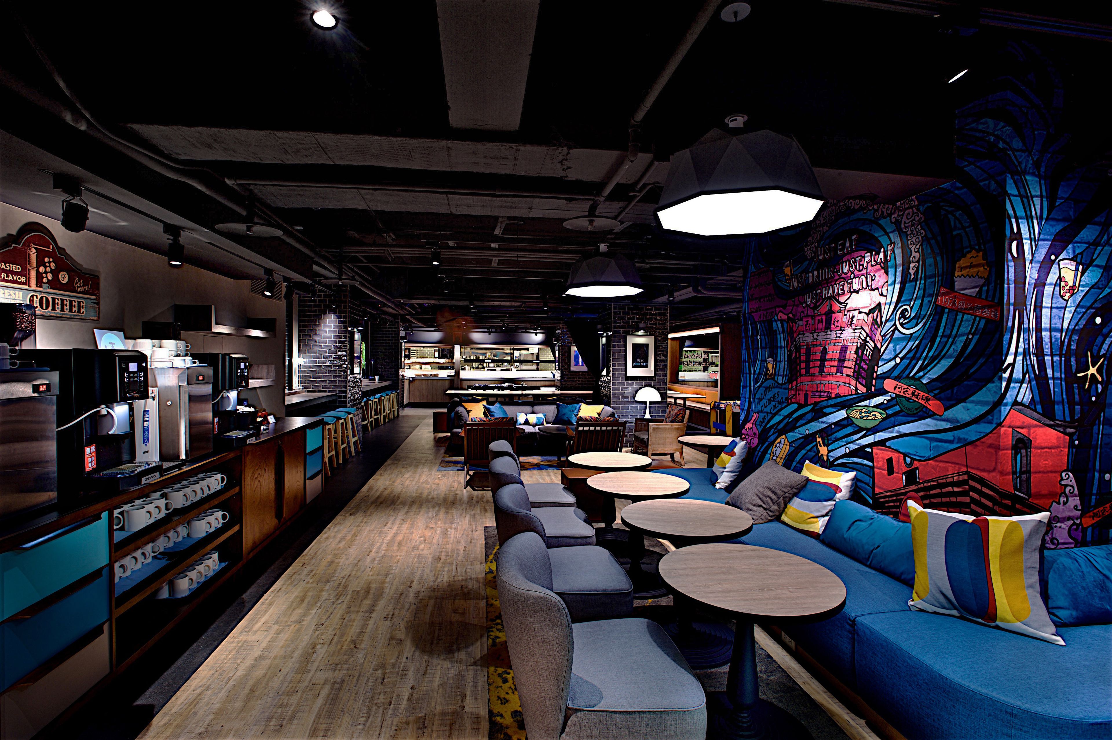 A modern cafe with a bar area, seating, and a colorful mural on the wall.