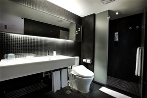 Un baño moderno con pared de azulejos negros, un lavabo blanco y un inodoro.