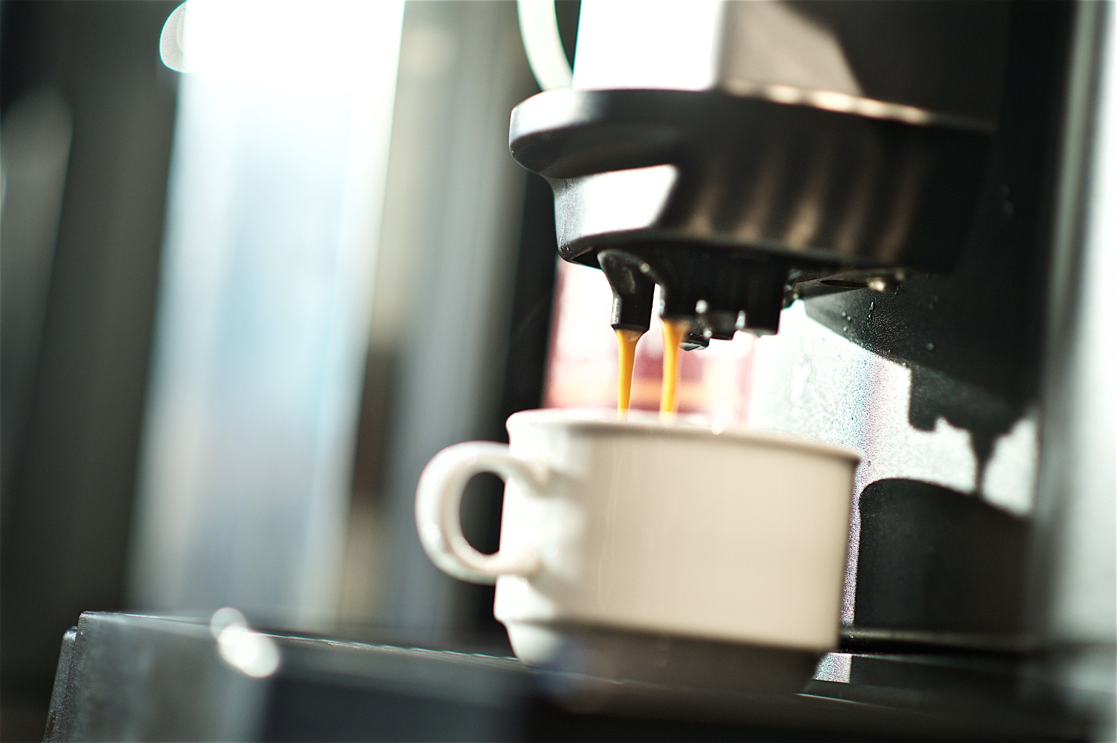 Eine Kaffeemaschine füllt Kaffee in eine Tasse.