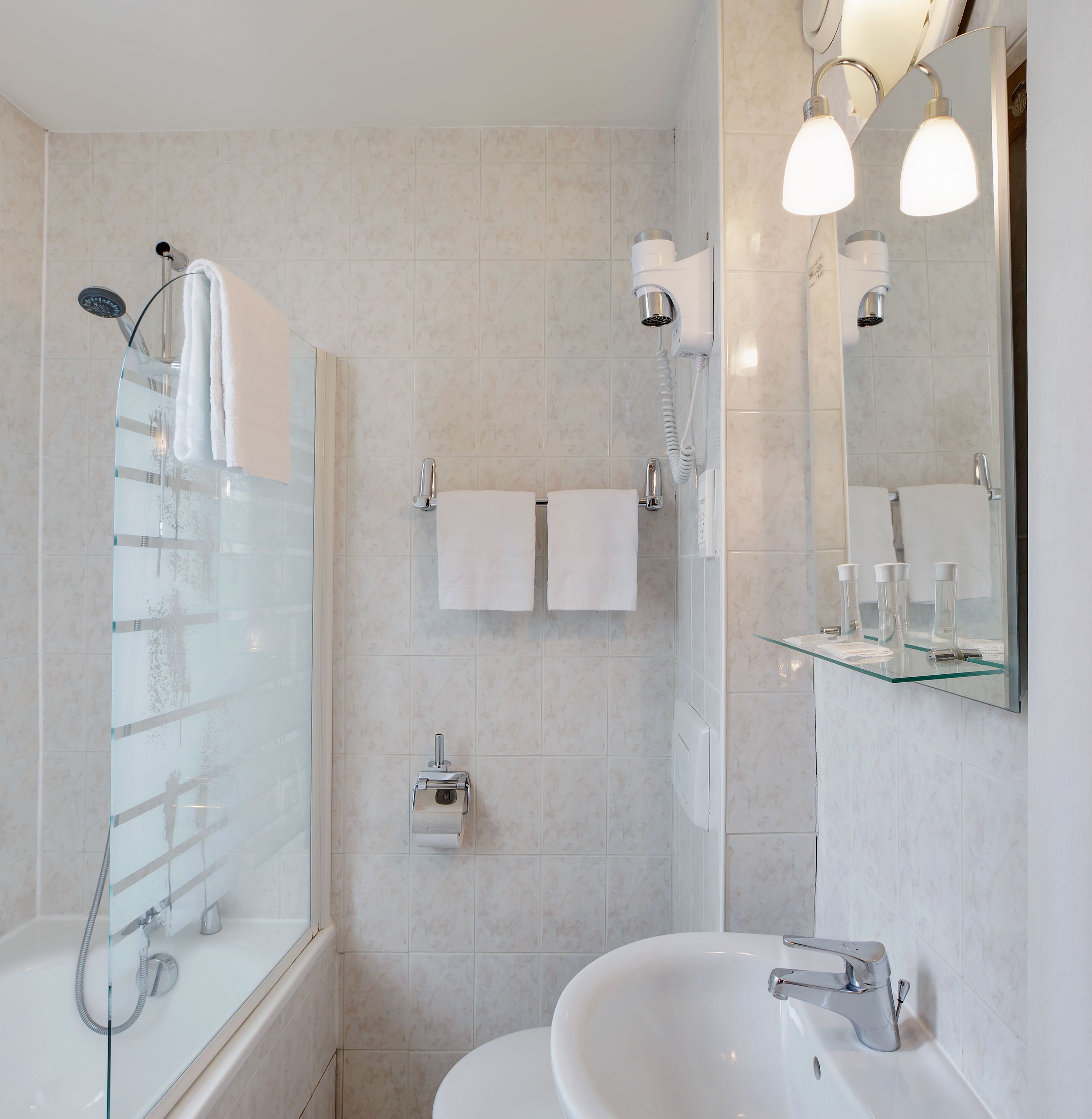 Un baño moderno con ducha envuelta en cristal, un lavabo blanco y un espejo con iluminación.