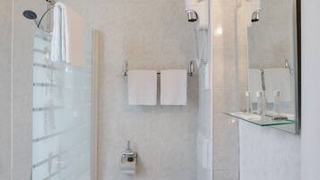 Un baño moderno con ducha envuelta en cristal, un lavabo blanco y un espejo con iluminación.