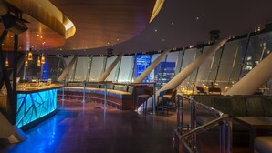 A modern interior with a bar area, seating, and large windows offering city views. - Aloft by Marriott Abu Dhabi (Abu Dhabi)