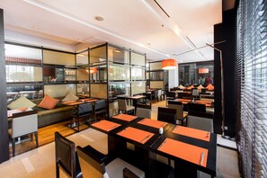 A modern restaurant with glass partitions, orange table settings, and contemporary lighting. - Signature Pattaya Hotel (Pattaya)
