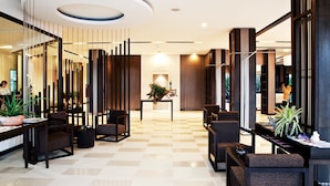 A modern lobby with a checkered floor, seating areas, and a central plant. - Signature Pattaya Hotel (Pattaya)