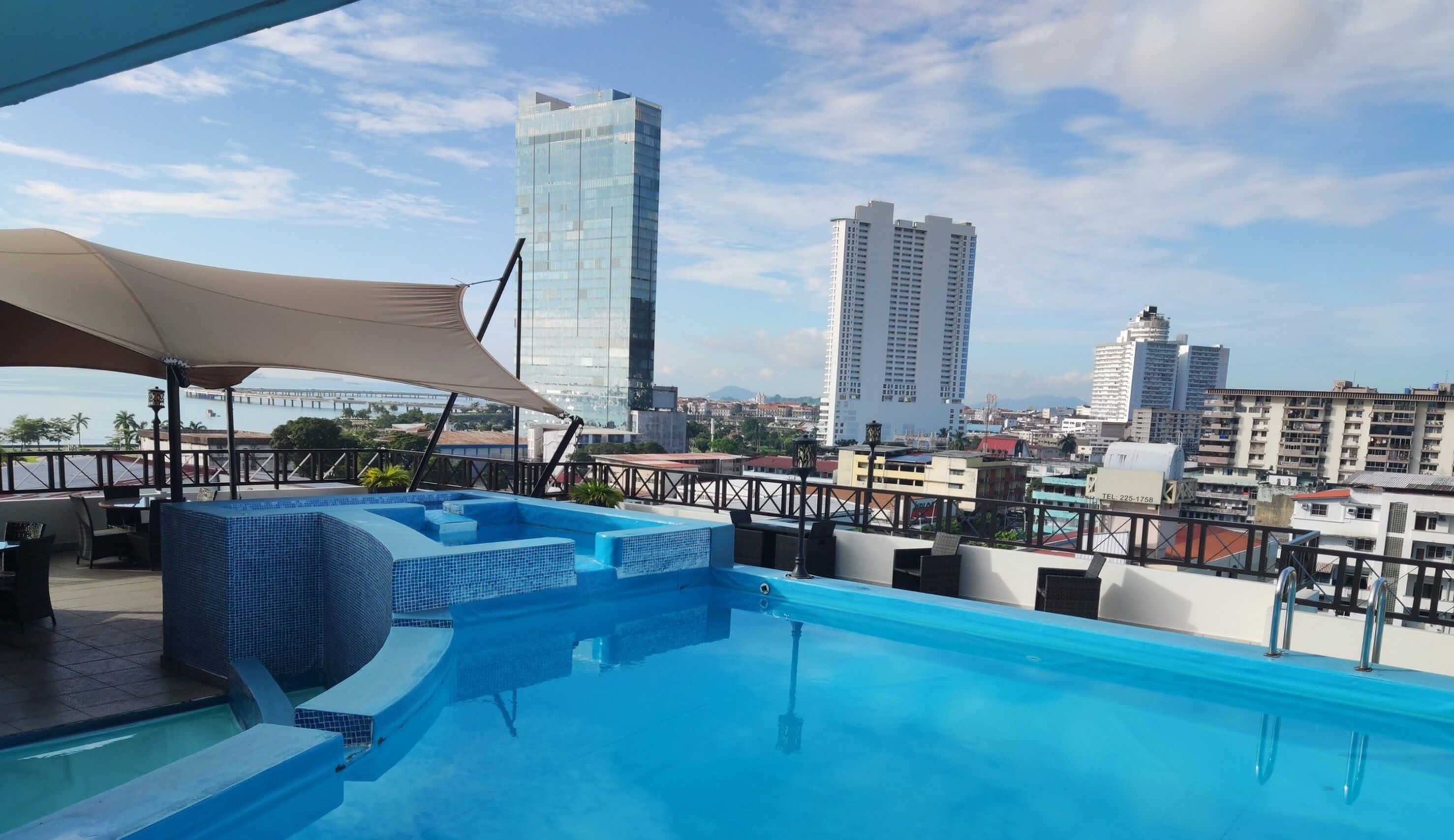 A rooftop pool with a city view, including high-rise buildings and a bridge.