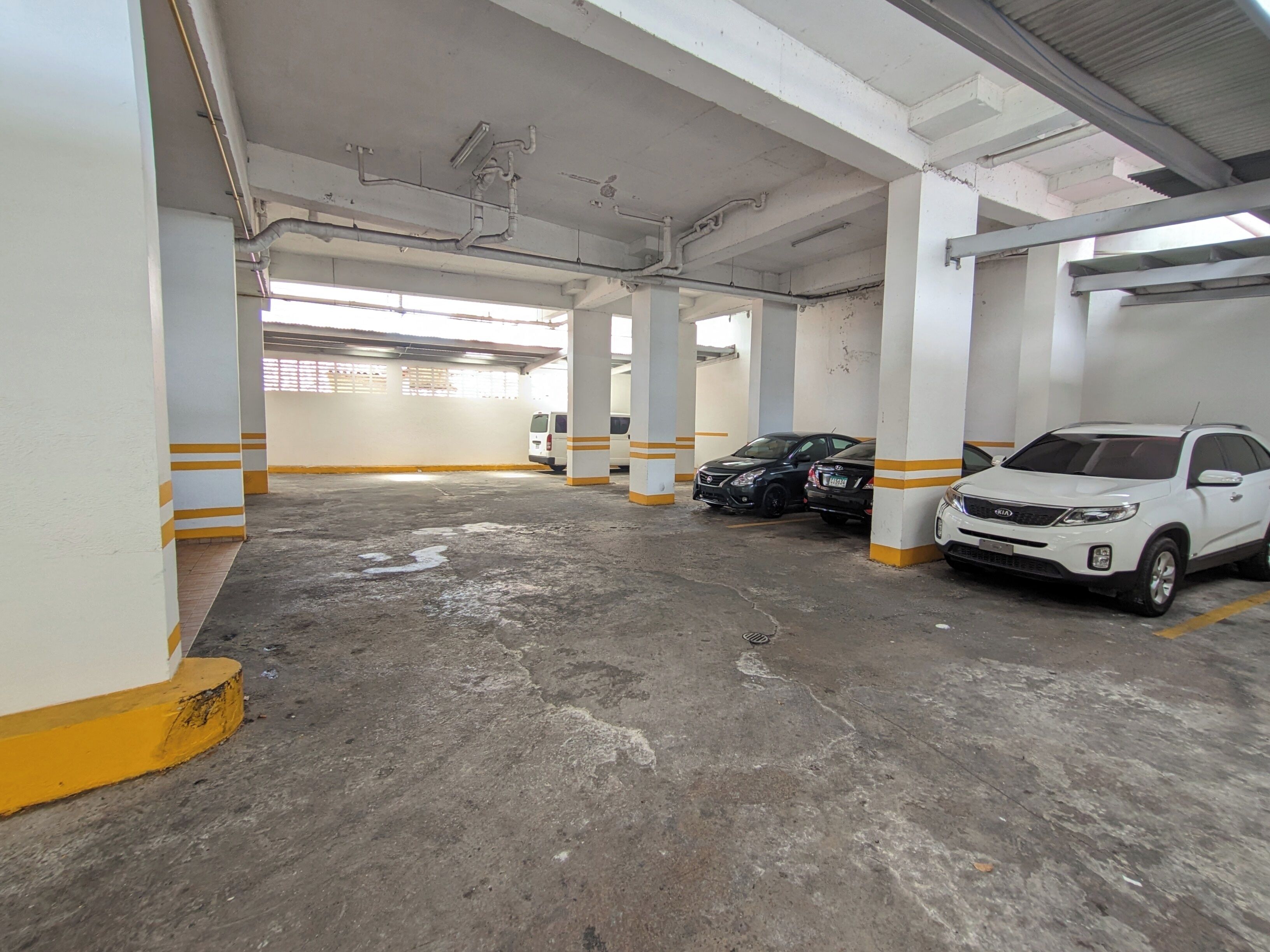 Un estacionamiento con pisos de concreto y pilares blancos con franjas amarillas.