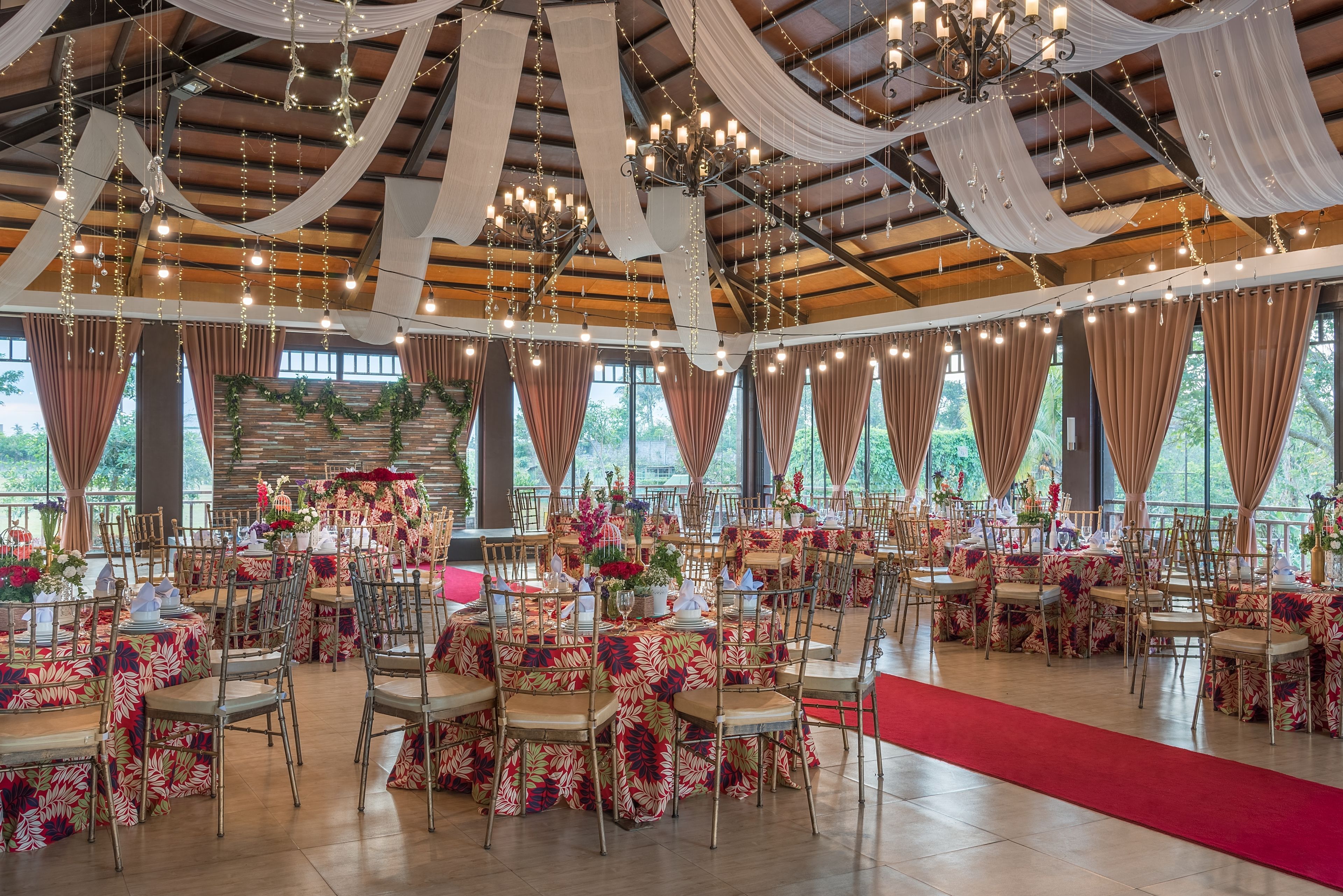 Una sala de banquetes amb taules rodones, cadires i una catifa vermella.