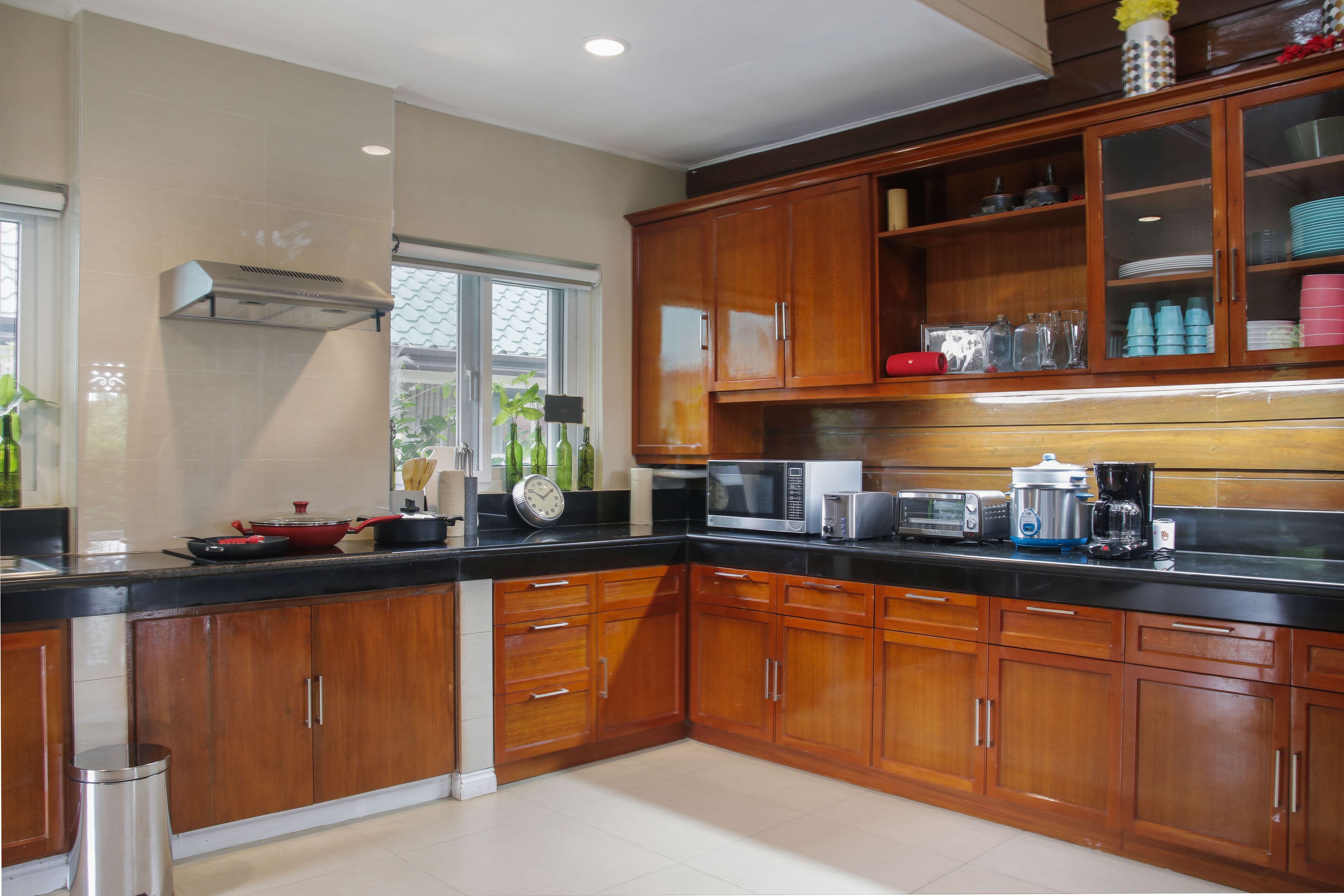 A modern kitchen with wooden cabinets, a black countertop, and various appliances including a microwave, toaster, and coffee maker.