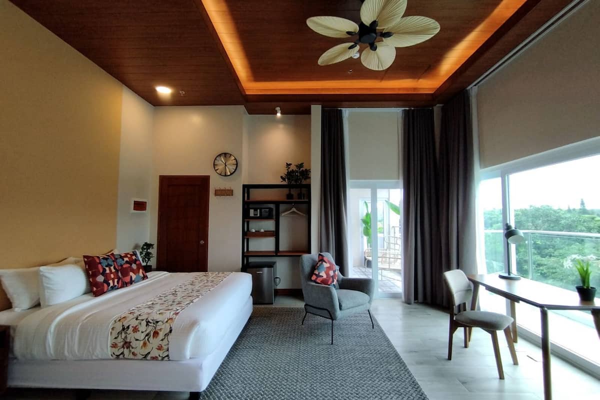 Une chambre d’hôtel moderne dotée d’un grand lit, d’un bureau, d’une chaise et d’un balcon avec vue.